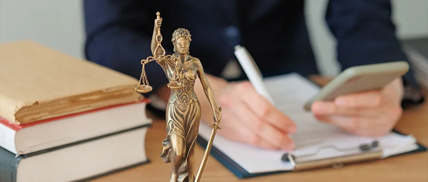 A law professional working at a desk with a Lady Justice figurine